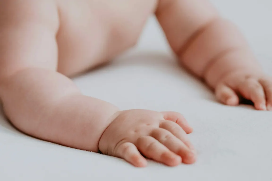 Kleine Hände eines Neugeborenen auf einer weichen Decke – Symbol für erfüllten Kinderwunsch.